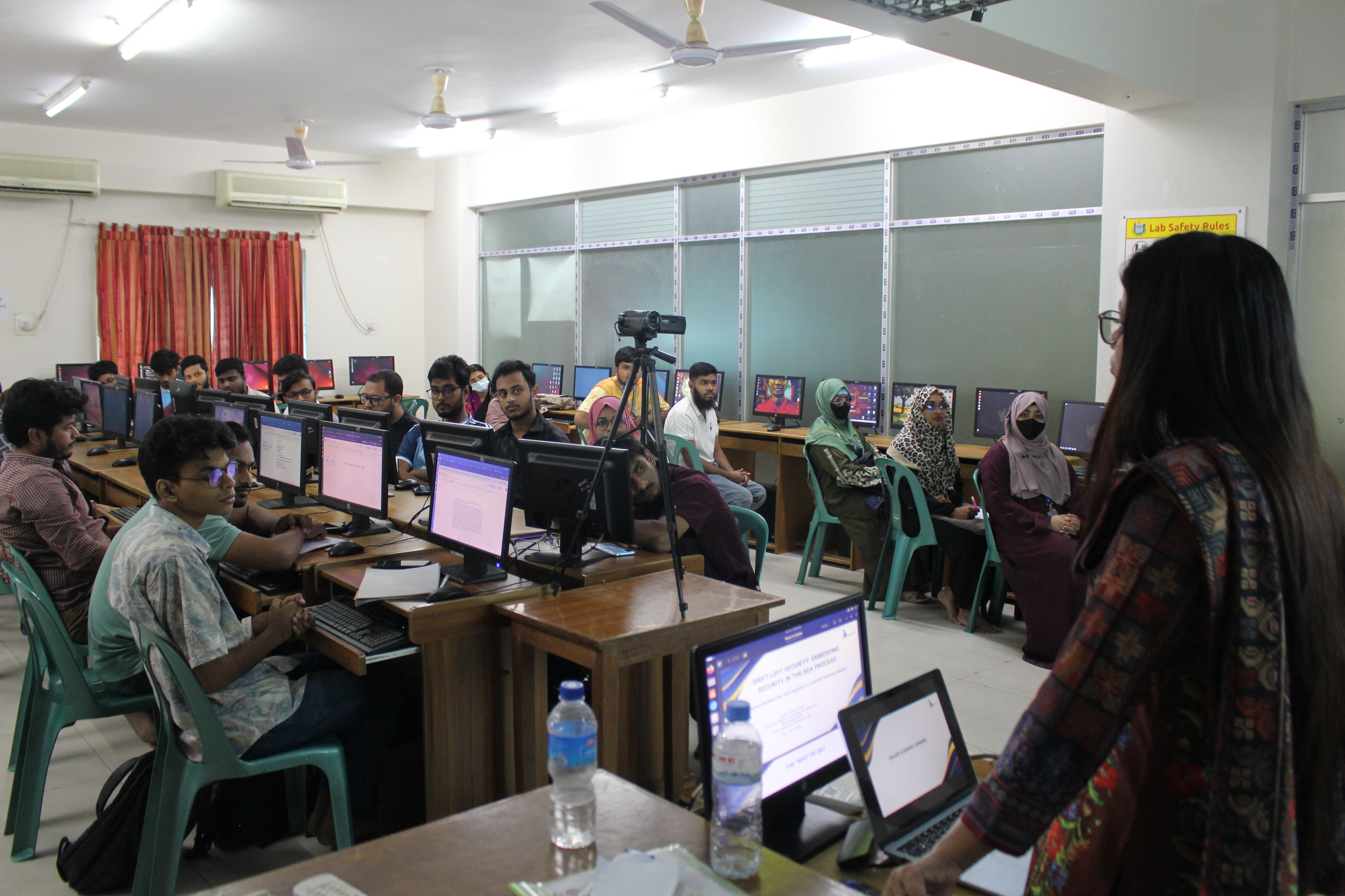 Students at workstations in a BUBT computer lab during the BugBoundQA SQA workshop, with the trainer presenting at the front of the room.