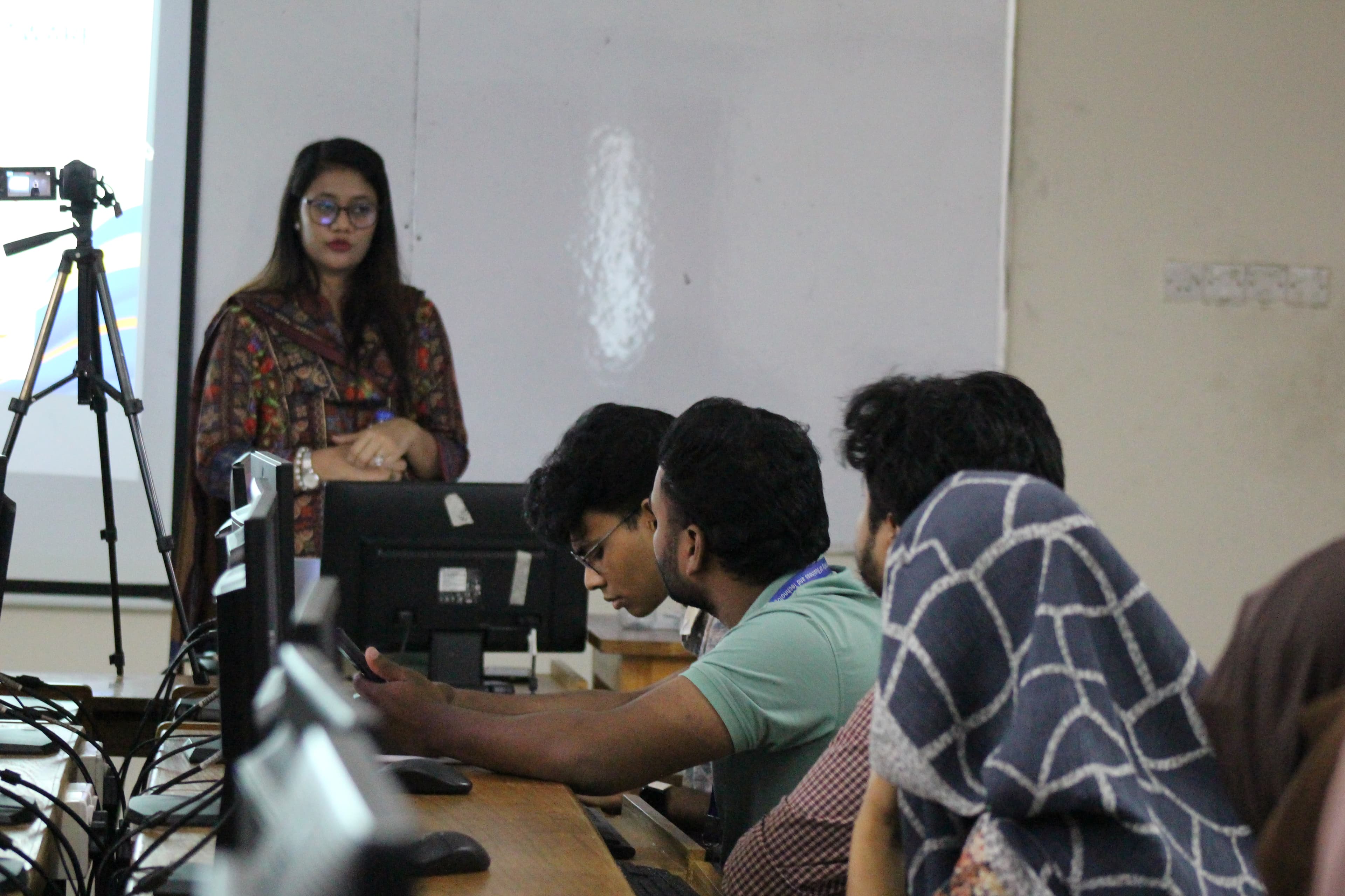 The BugBoundQA trainer presenting beside a projector screen while students follow along at their computers.