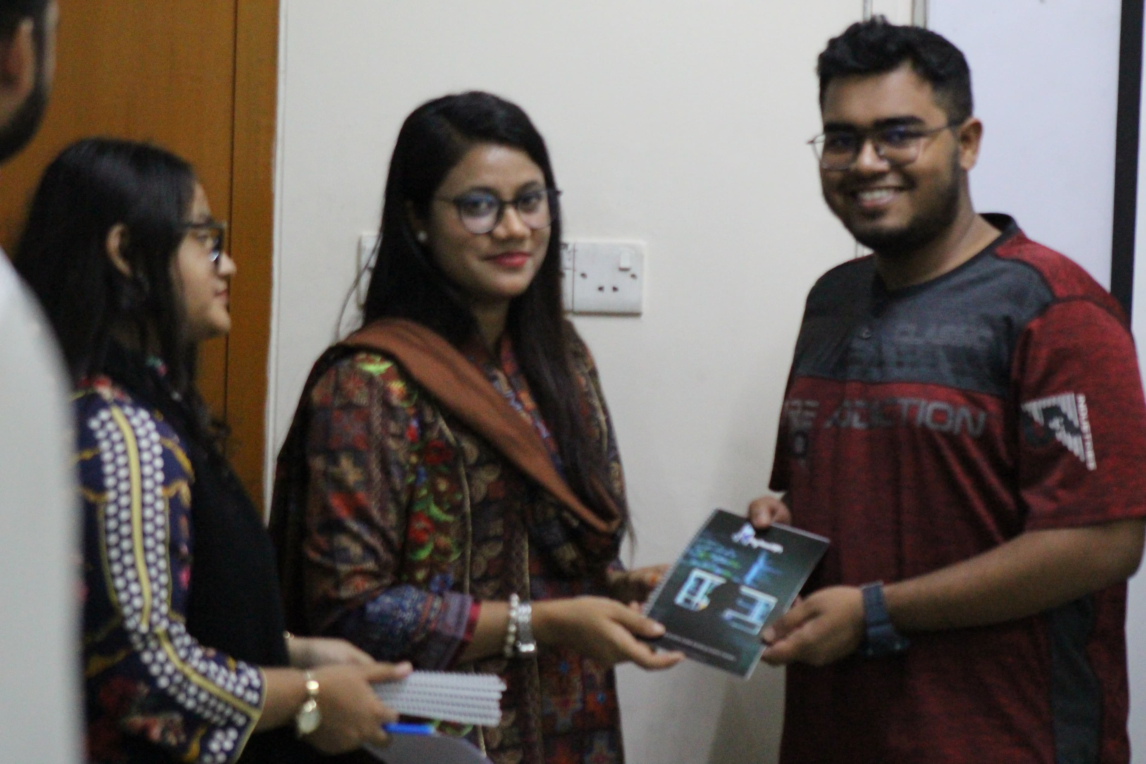 A workshop participant receiving a BugBoundQA notebook from the trainer.