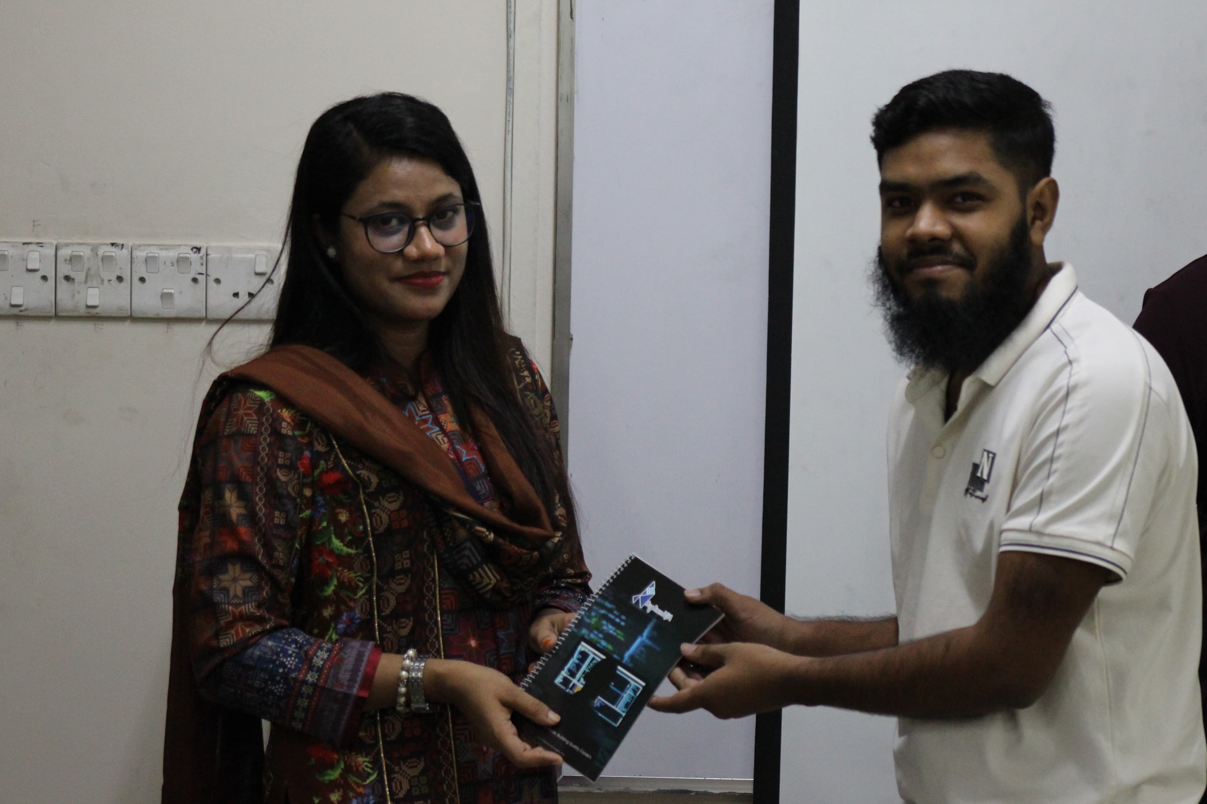 The trainer handing a BugBoundQA notebook to a participant who completed the workshop.