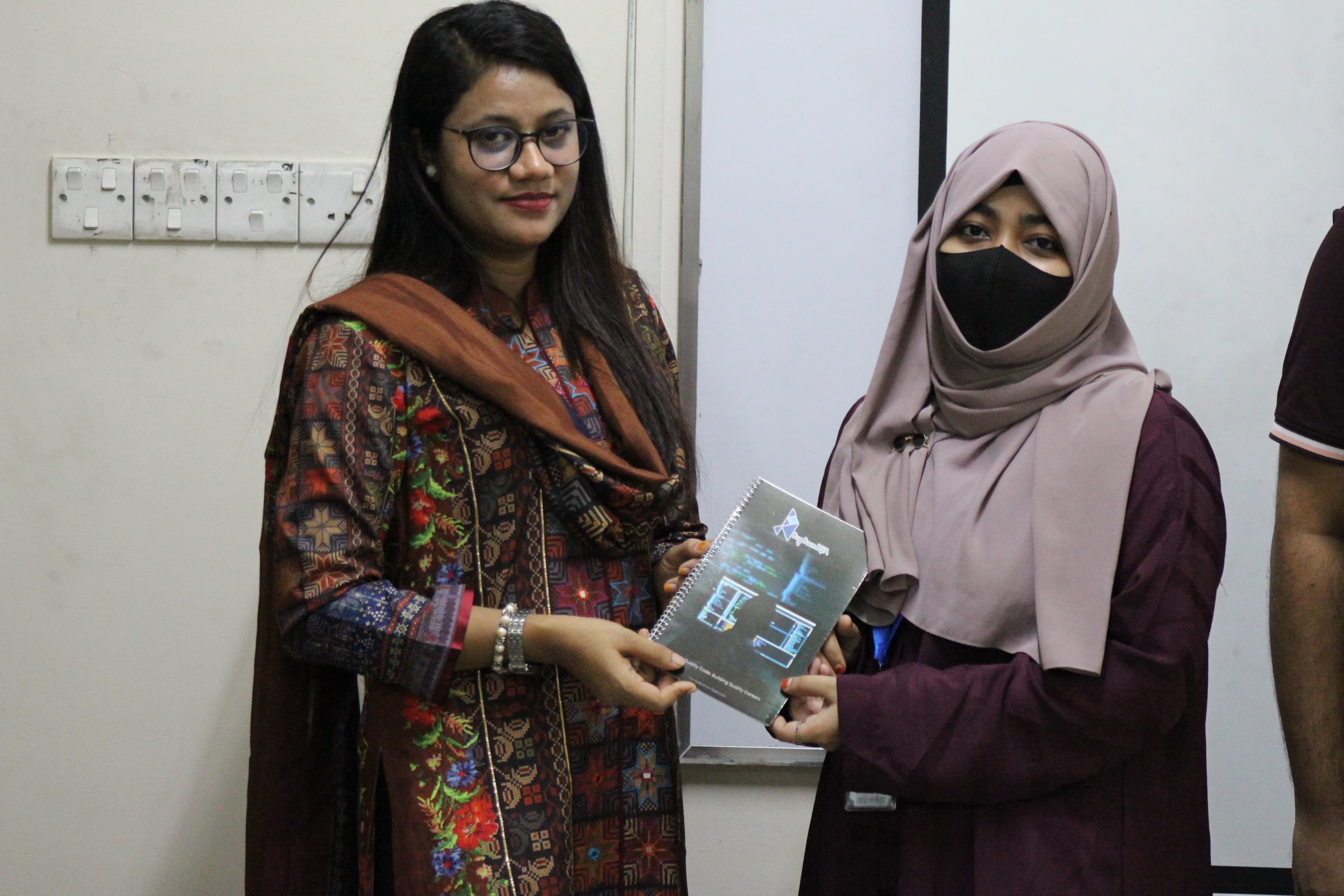 A student receiving her BugBoundQA notebook from the trainer at the BUBT workshop.